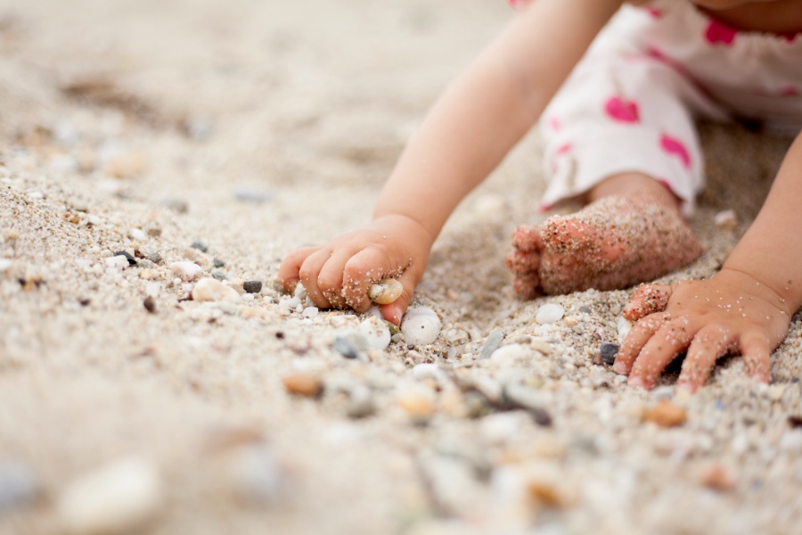 Part of cute baby girl playing in the sand
