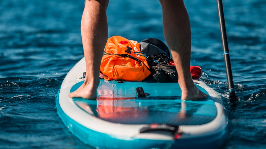 Young athletic man paddling on a SUP paddle board in blue water sea in Montenegro