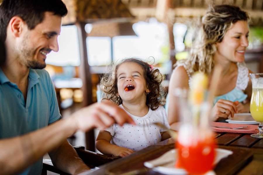 Happy girl enjoying with her parents during lunch in a restaurant